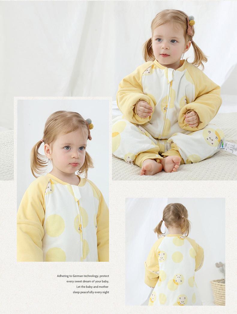 Baby wearing Dear Kora cotton sleeping sack in yellow pattern.
